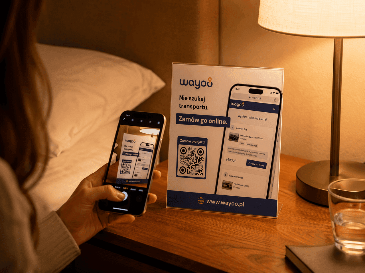 Gość hotelowy skanuje telefonem kod QR Wayoo ze stojaka przy łóżku